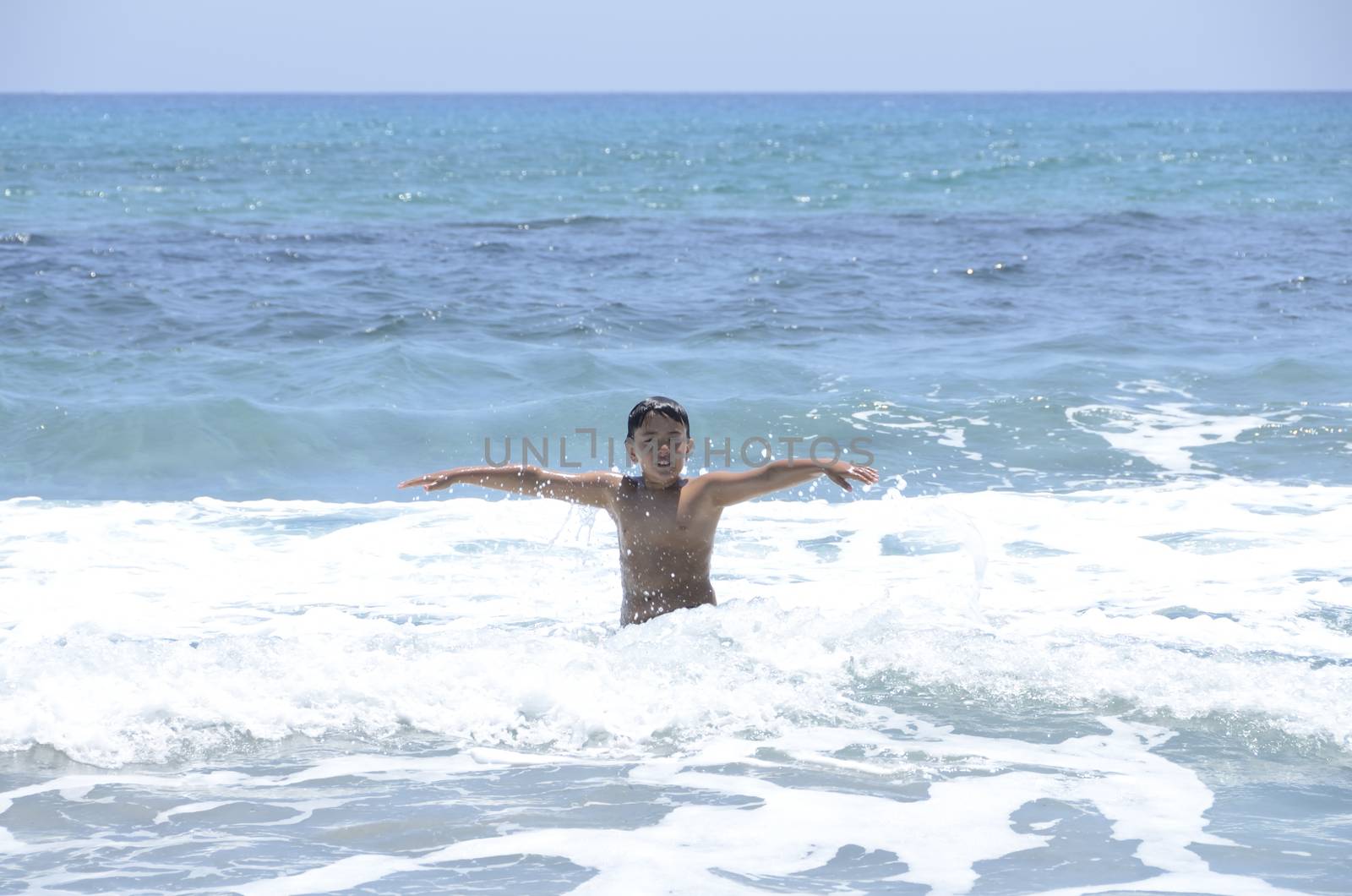 Happy summer for the child at the beach with the waves and splashing water.