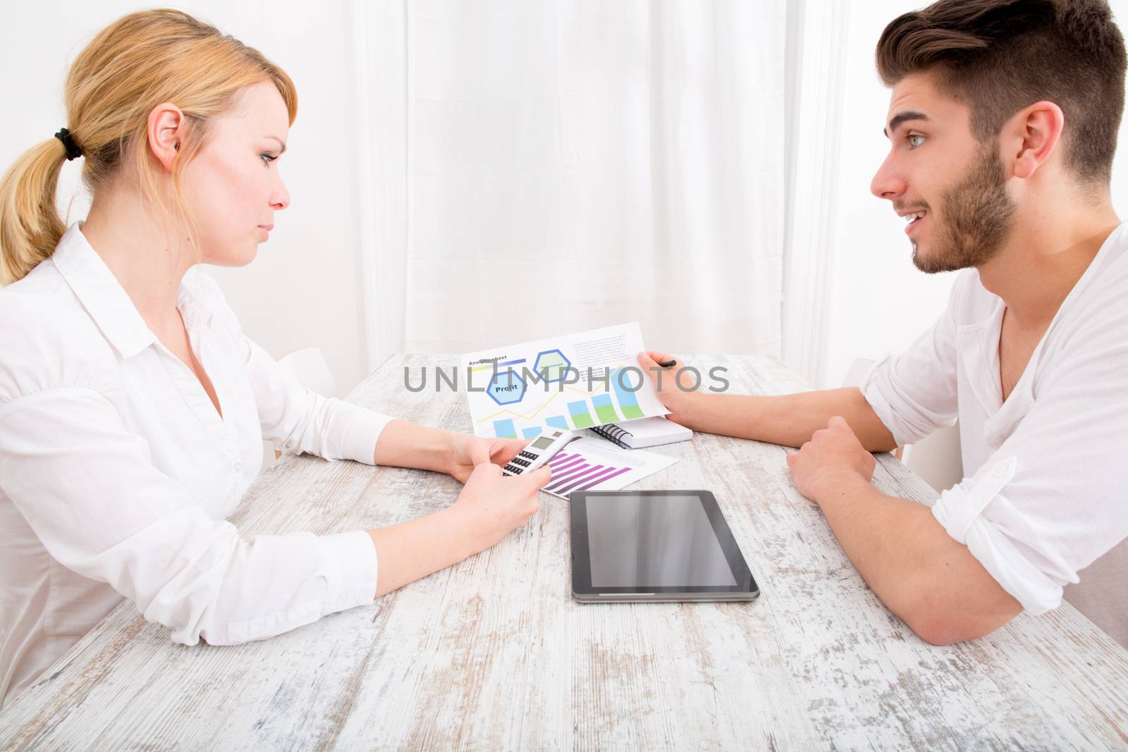 A young couple organizing their financial situation at home.
