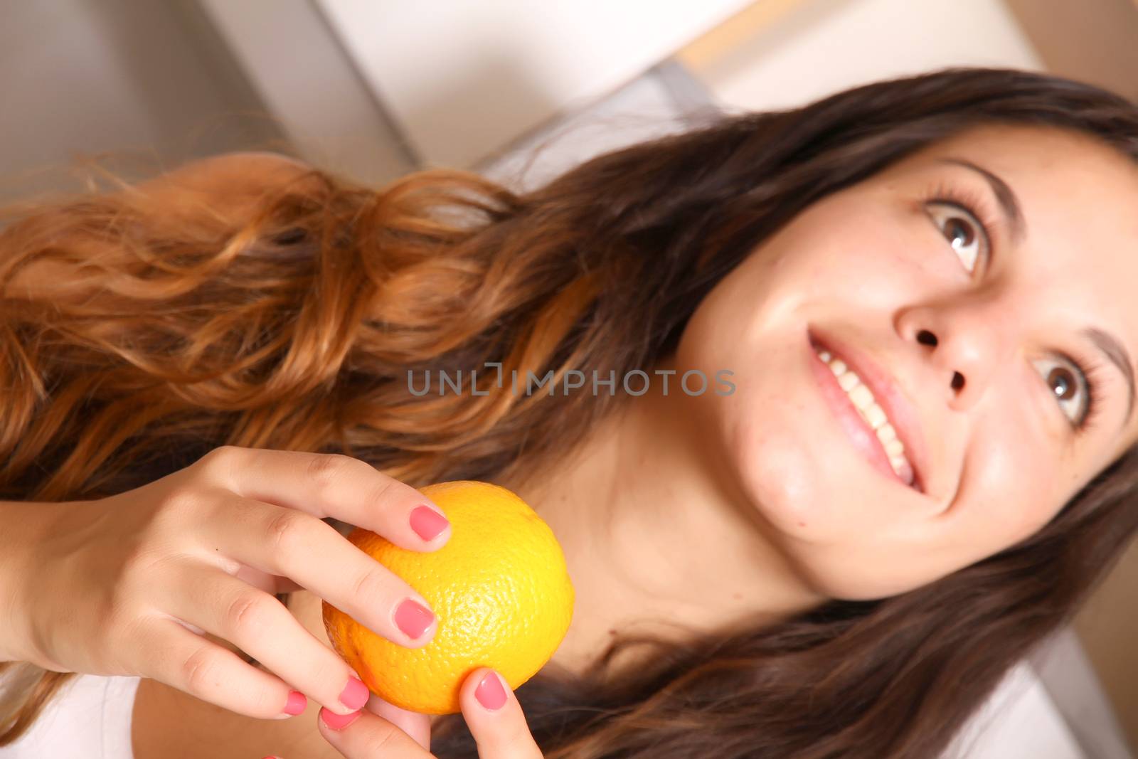 A young adult woman with fruits in the kitchen.