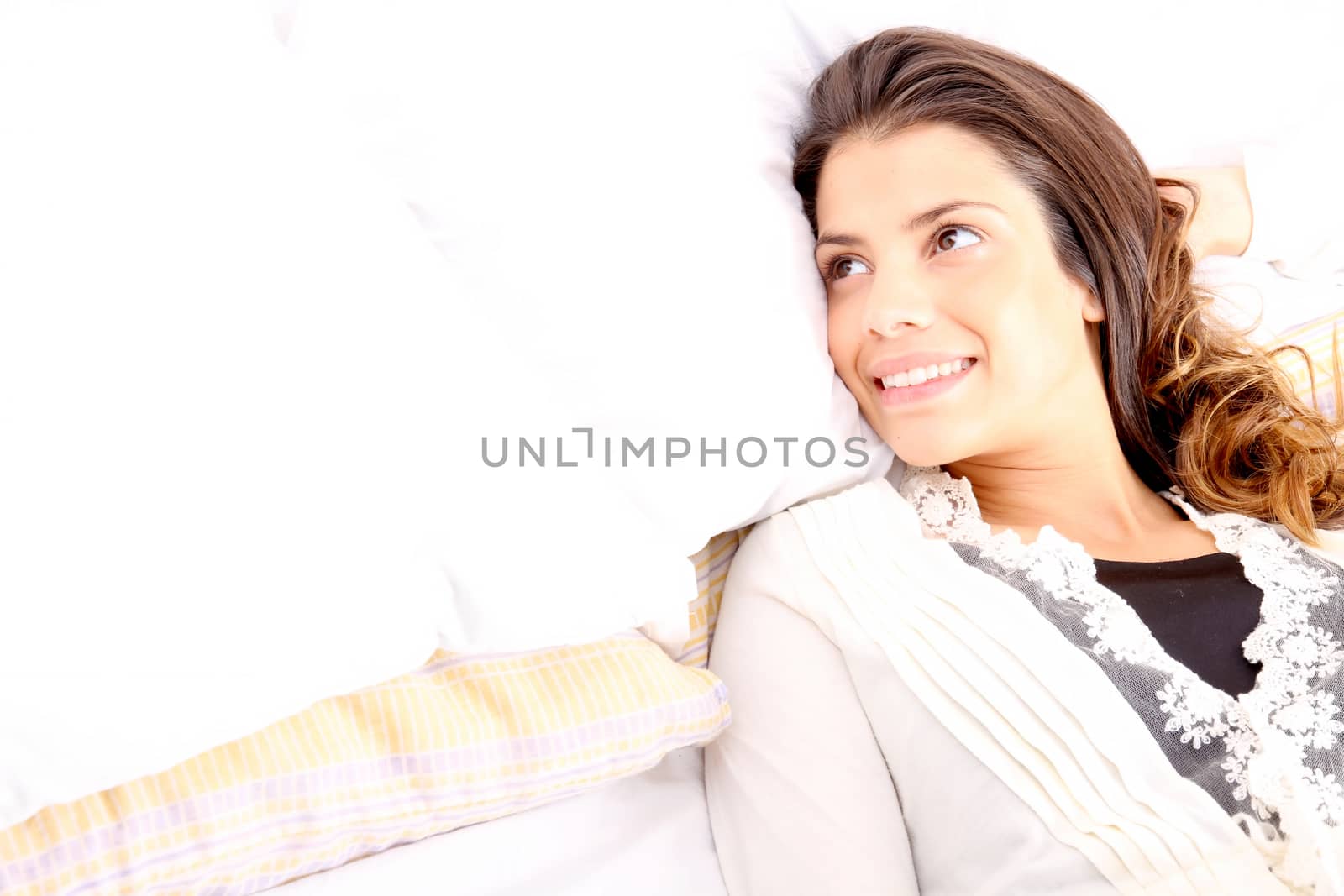 A young girl laying in bed and smiling
