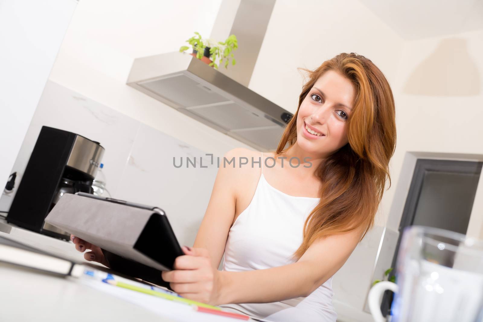 Portrait of a redhead girl holding a tablet pc in the kitchen.