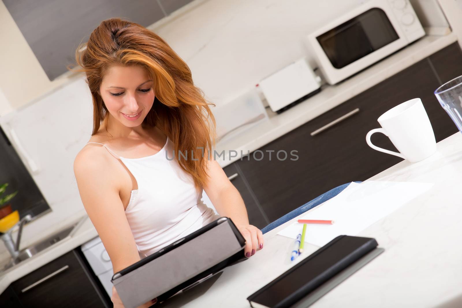 Redhead girl holding tablet pc in kitchen by Spectral