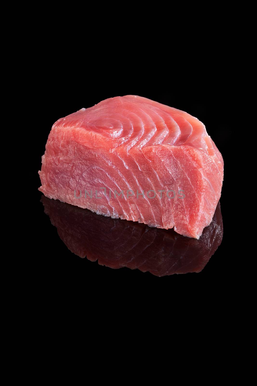 Fresh big tuna steak isolated on black background. Sashimi sushi, seafood eating, healthy food.
