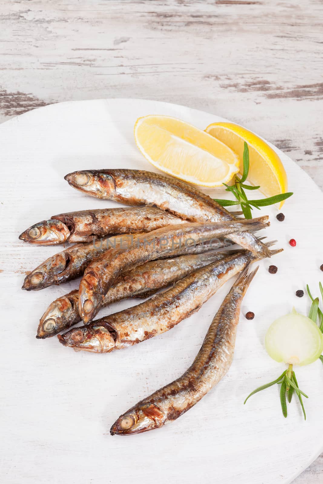 Culinary seafood eating. Grilled sardines on wooden background with fresh herbs and lemon. Culinary mediterranean eating. 