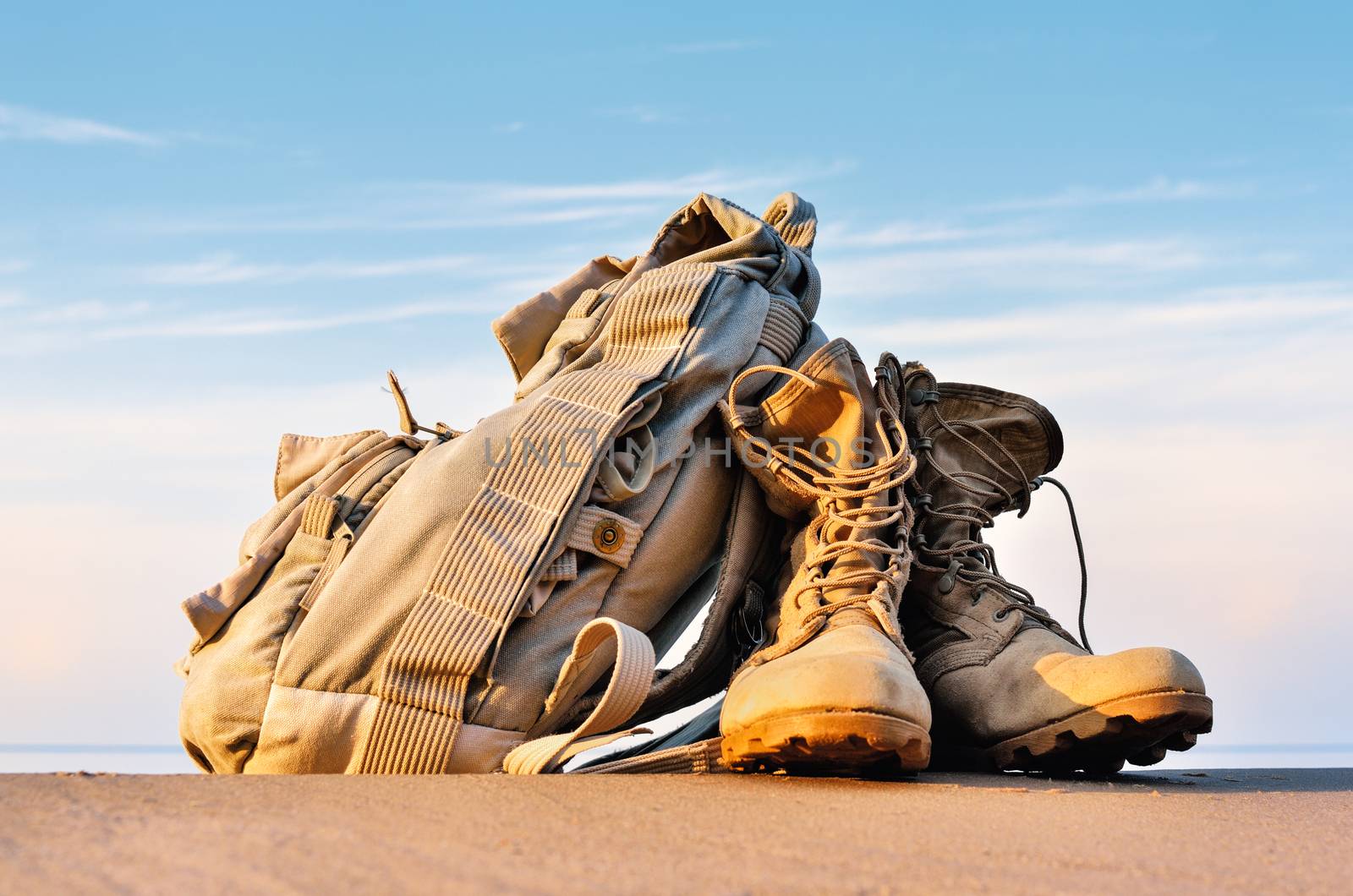 Yellow boots with a shoelaces and backpack on a sandy beach