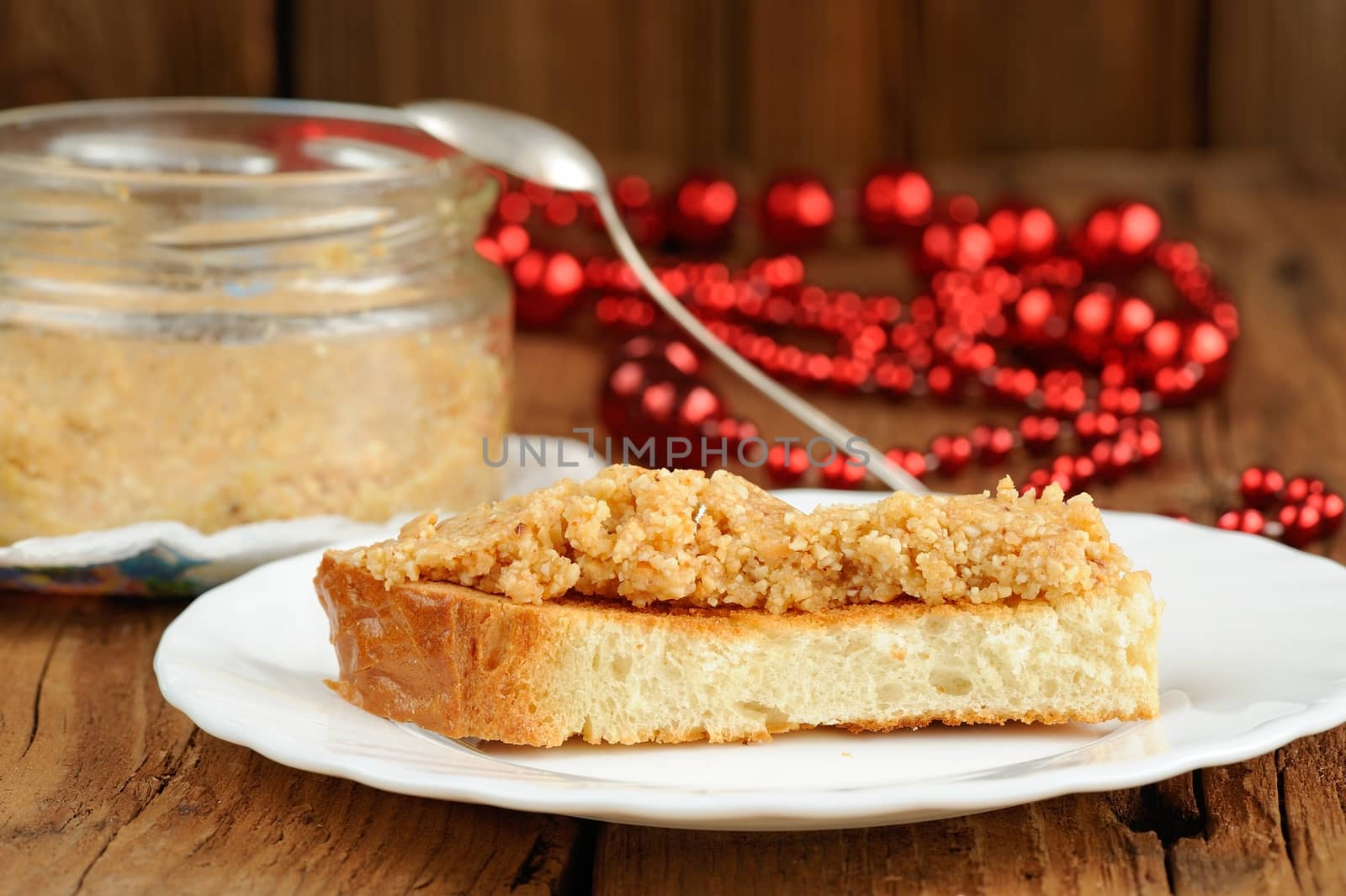 Homemade peanut paste on toast on white plate and wood background