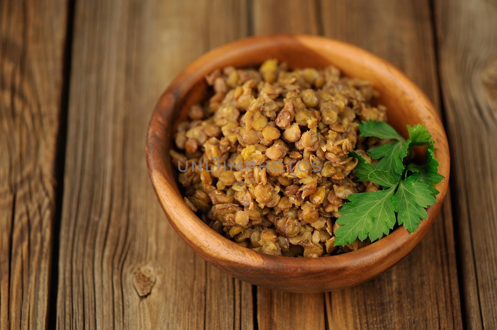 Cooked lentils in wooden bowl on the wooden background