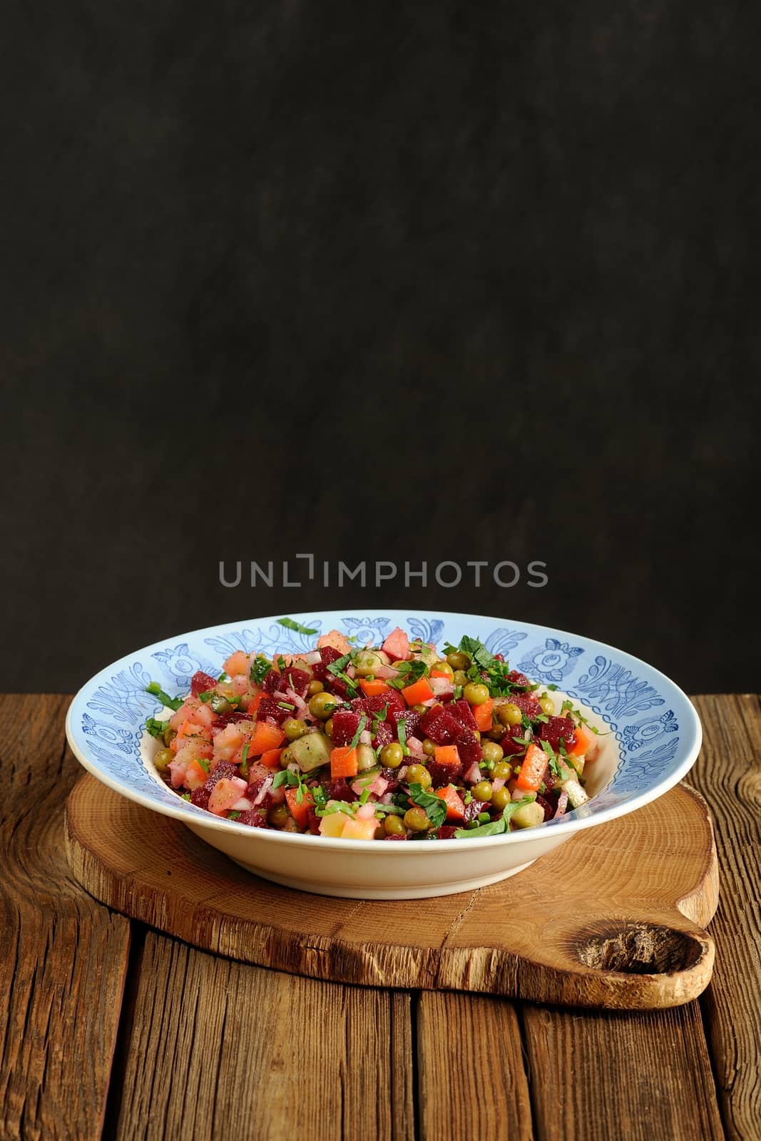 Russian beetroot salad vinegrette in blue plate on wooden background