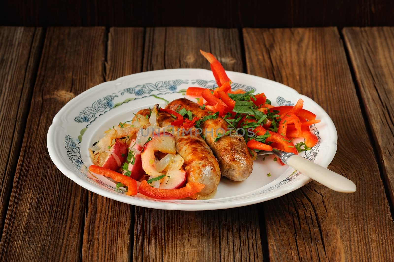 Fried sausages with fresh vegetables on wooden background