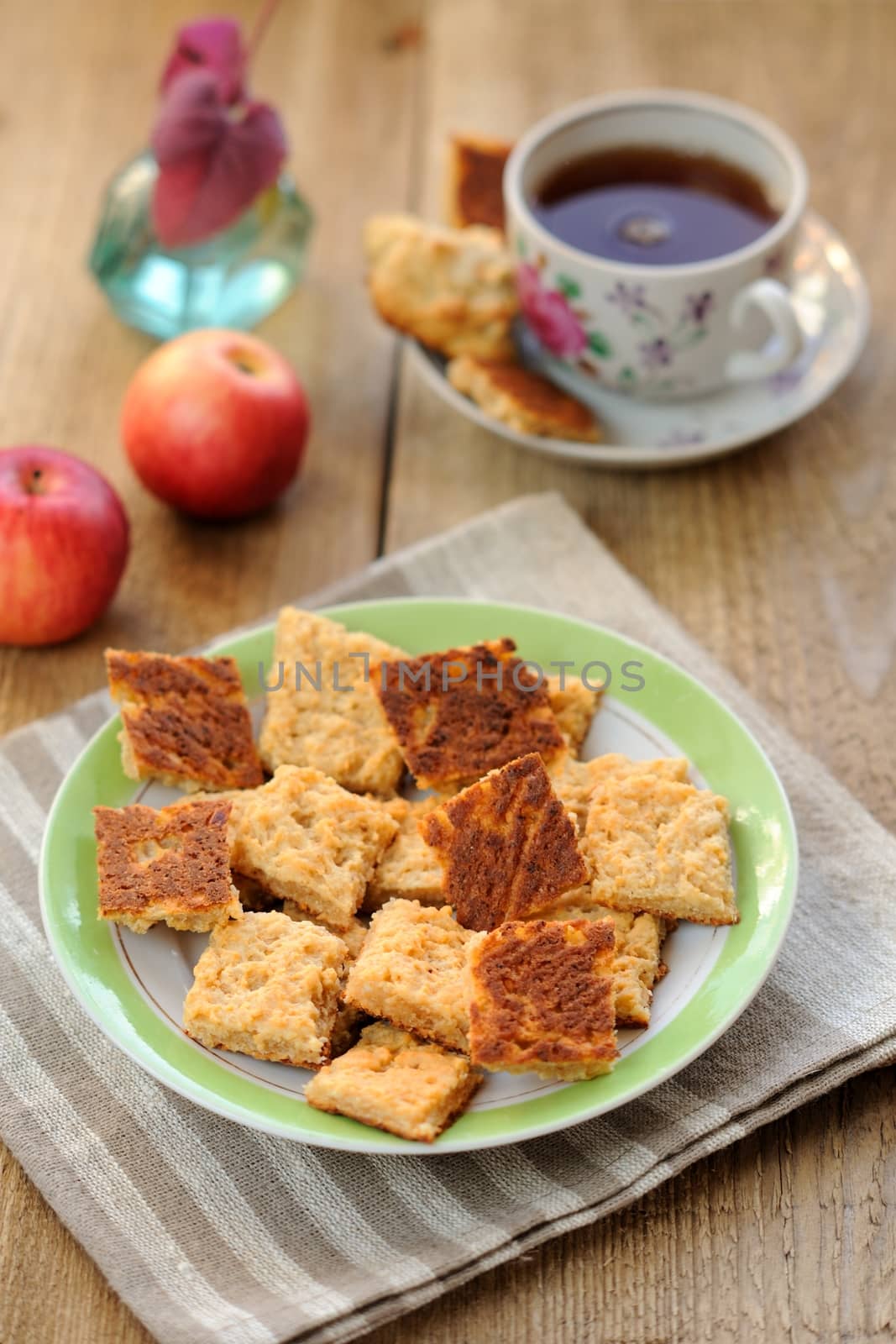 Black tea in a cup with cookies and apples on wooden background