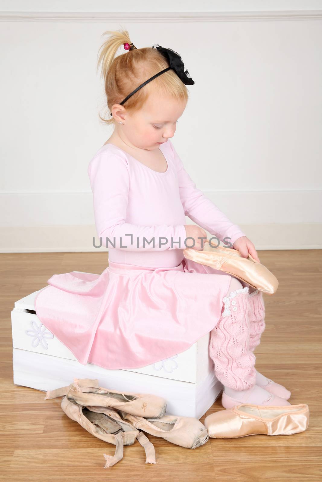 Little ballet girl trying on shoes at the ballet studio 