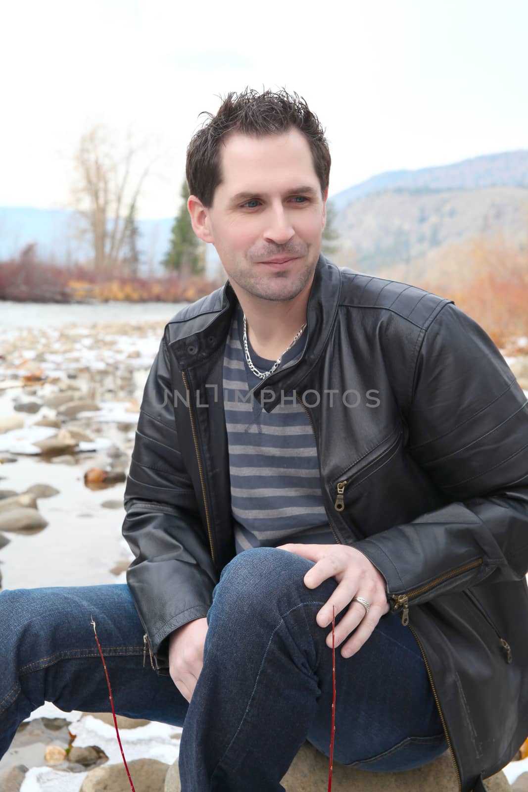 Attractive male outdoors wearing a black leather jacket 