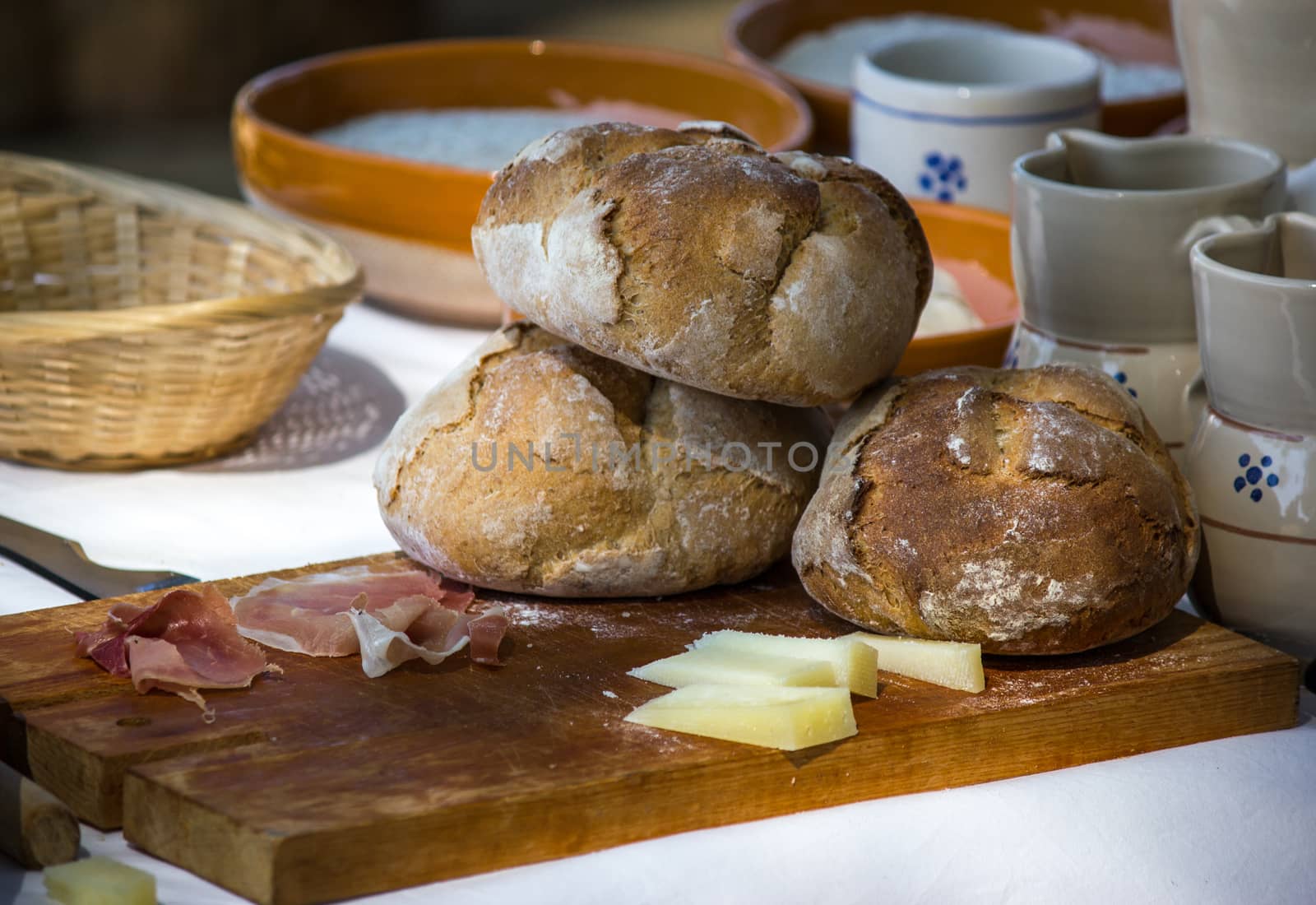 Freshly baked bread on cutting board with cheeses and cold cuts