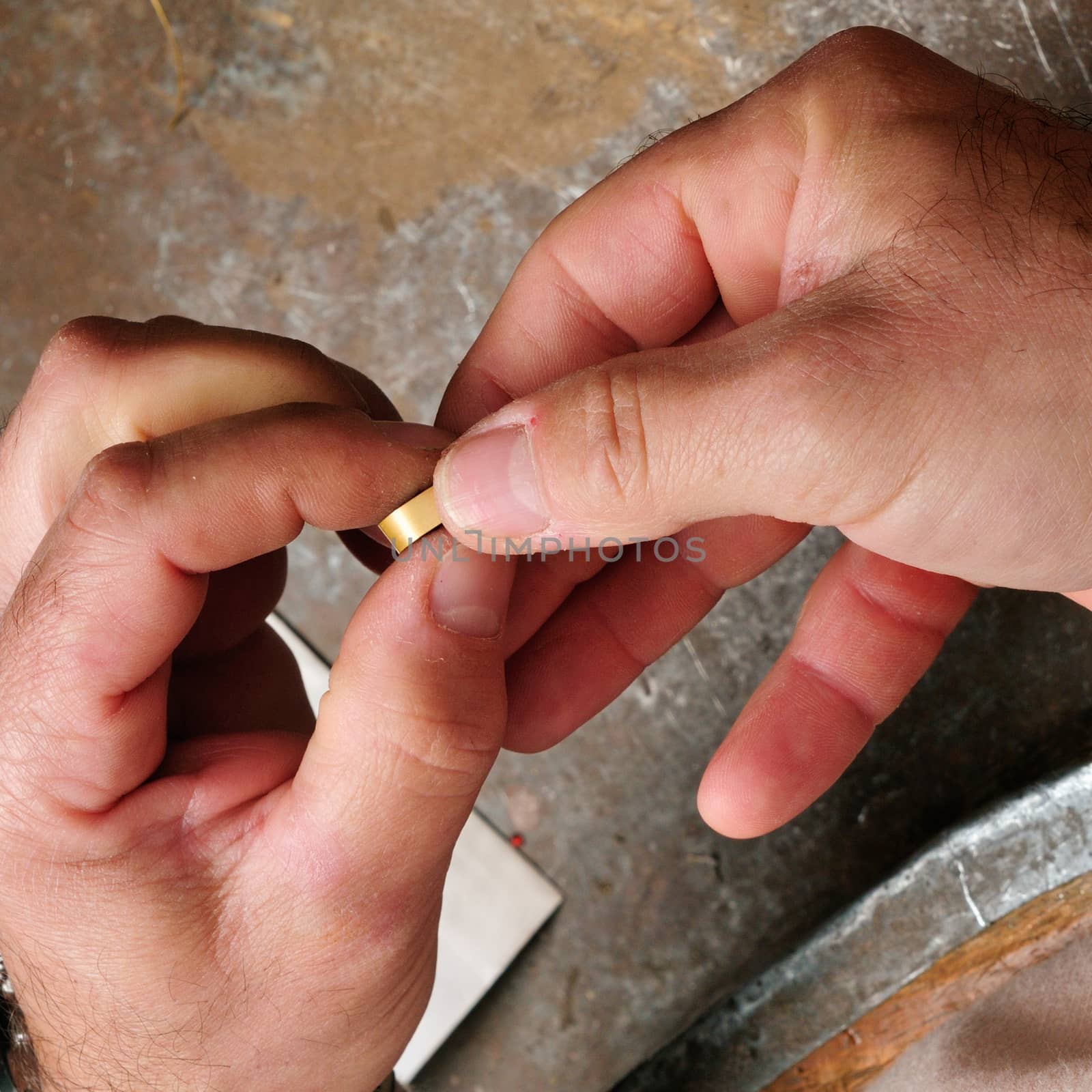 Skilled hands that create handmade jewelry with gold processing.