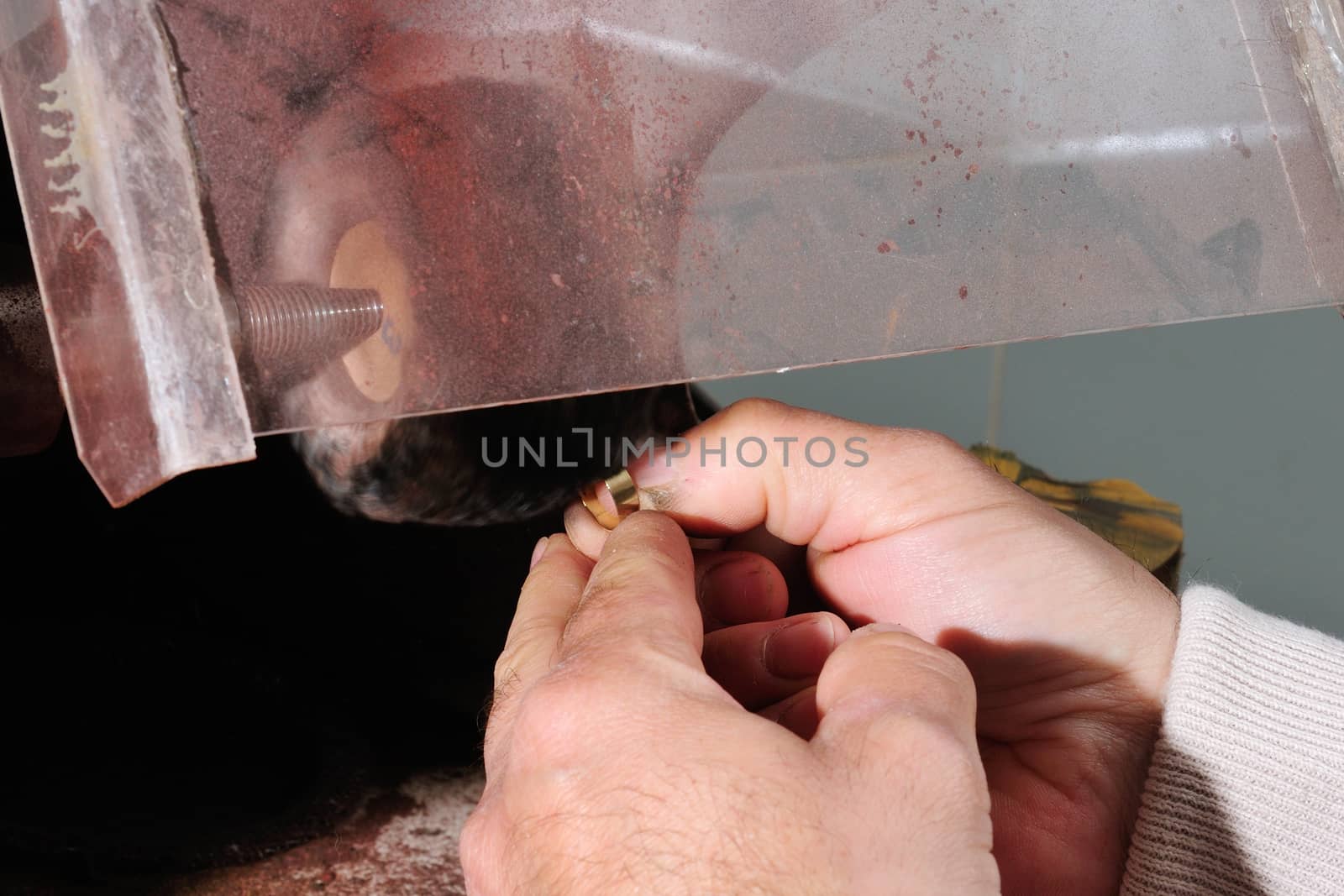 Skilled hands that create handmade jewelry with gold processing.