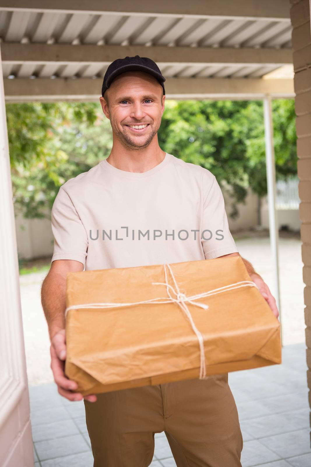 Delivery man smiling at camera offering parcel by Wavebreakmedia