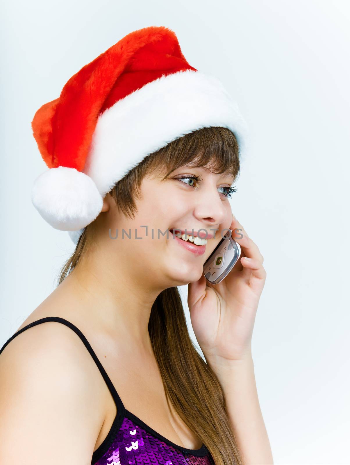 Attractive young woman in santa hat talking on the phone