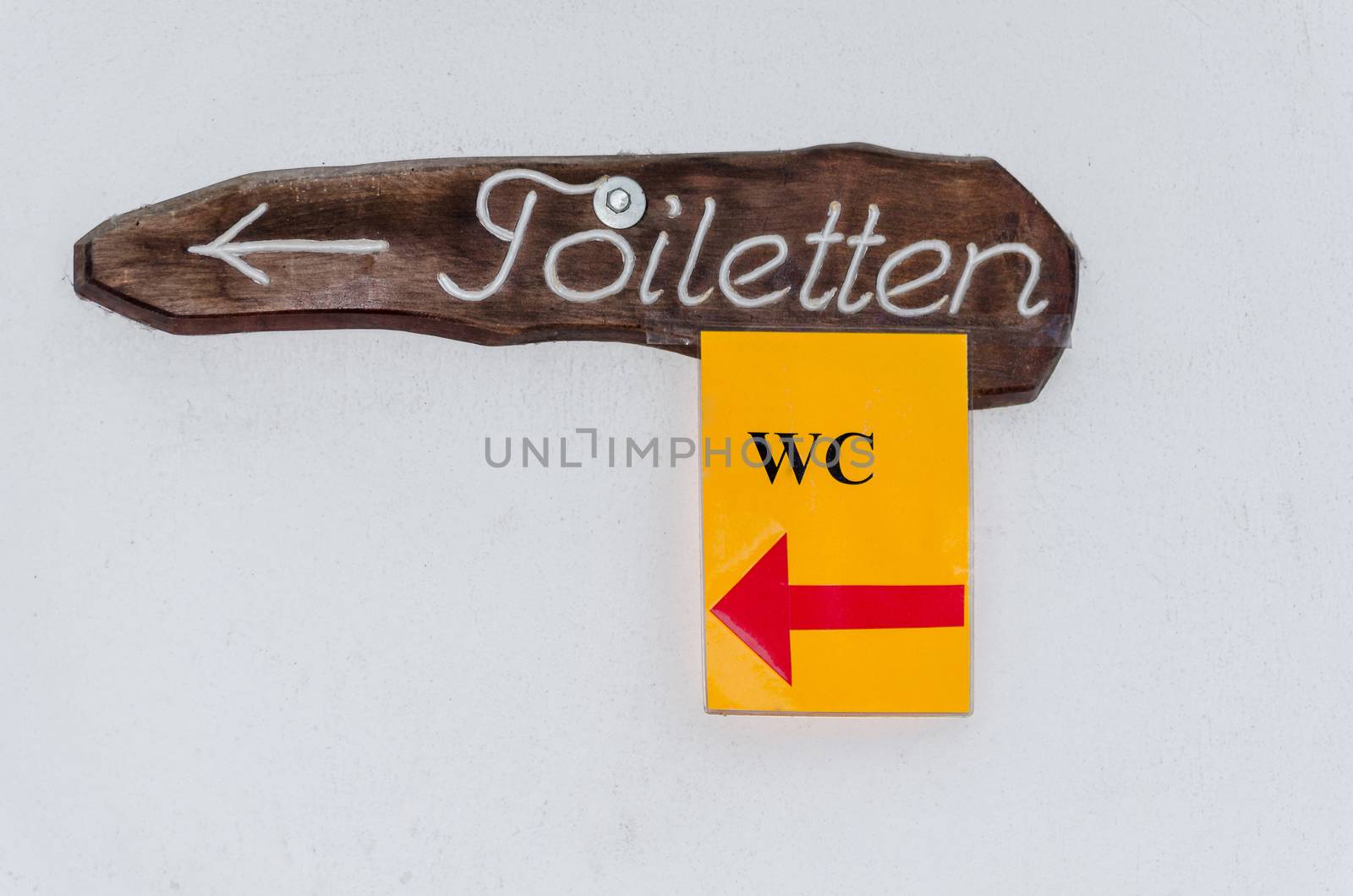 Wooden sign with inscription toilets with a small yellow sign toilet.