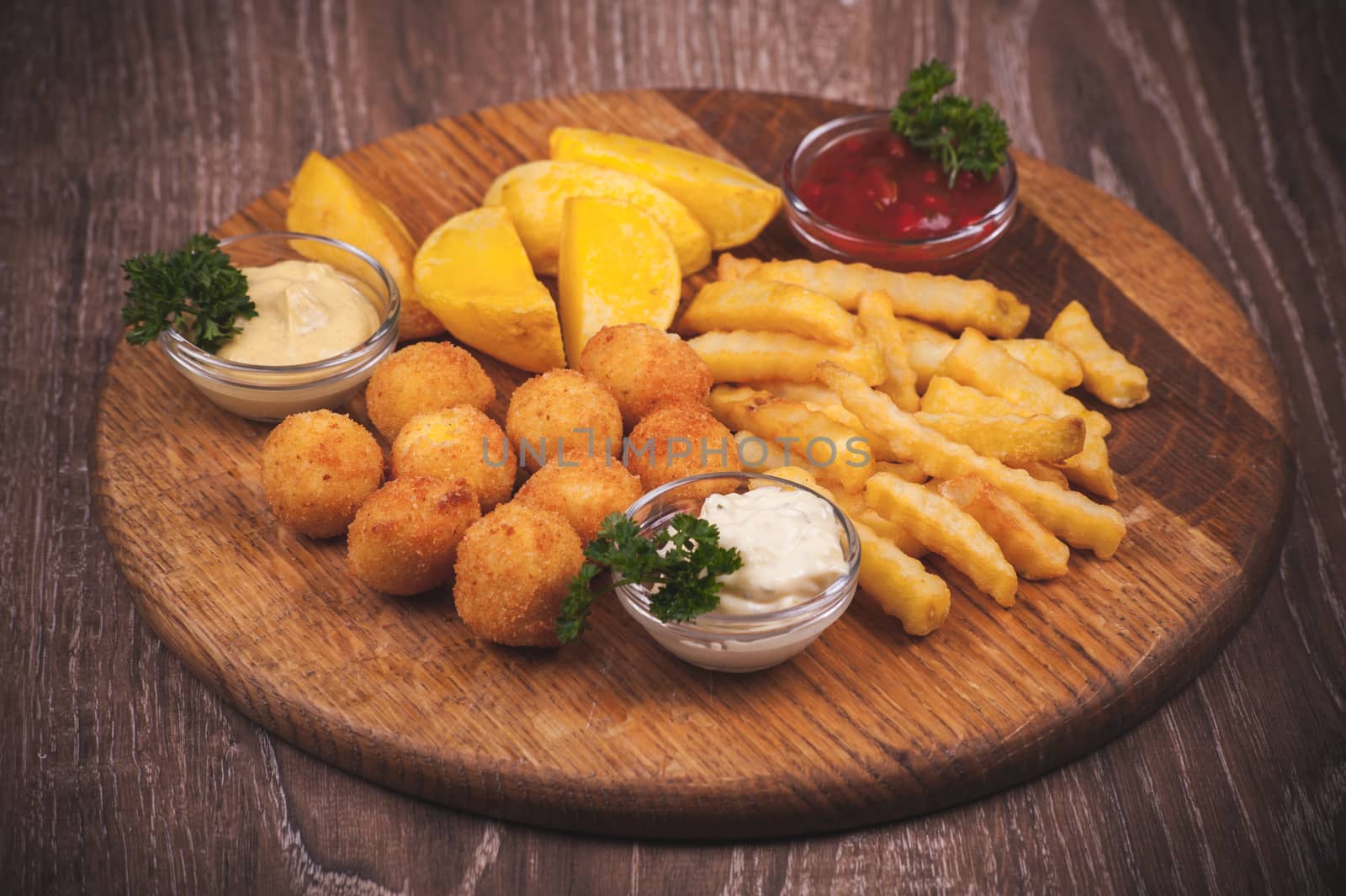 fried potato platter with dips  on wooden plate 