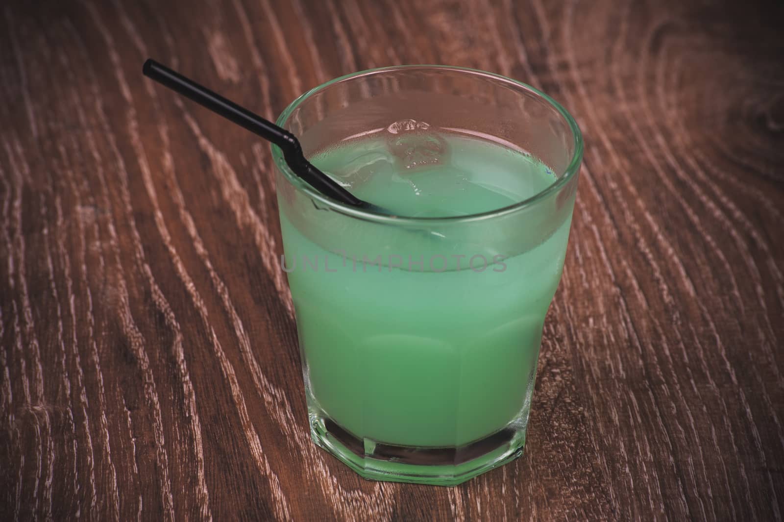 blue alcohol cocktail in glass with straw 