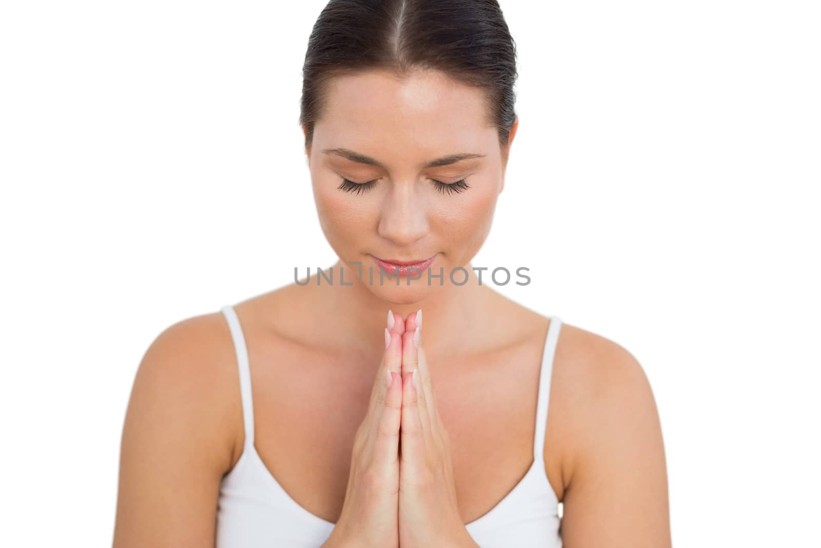 Peaceful brunette meditating with her eyes closed on white background