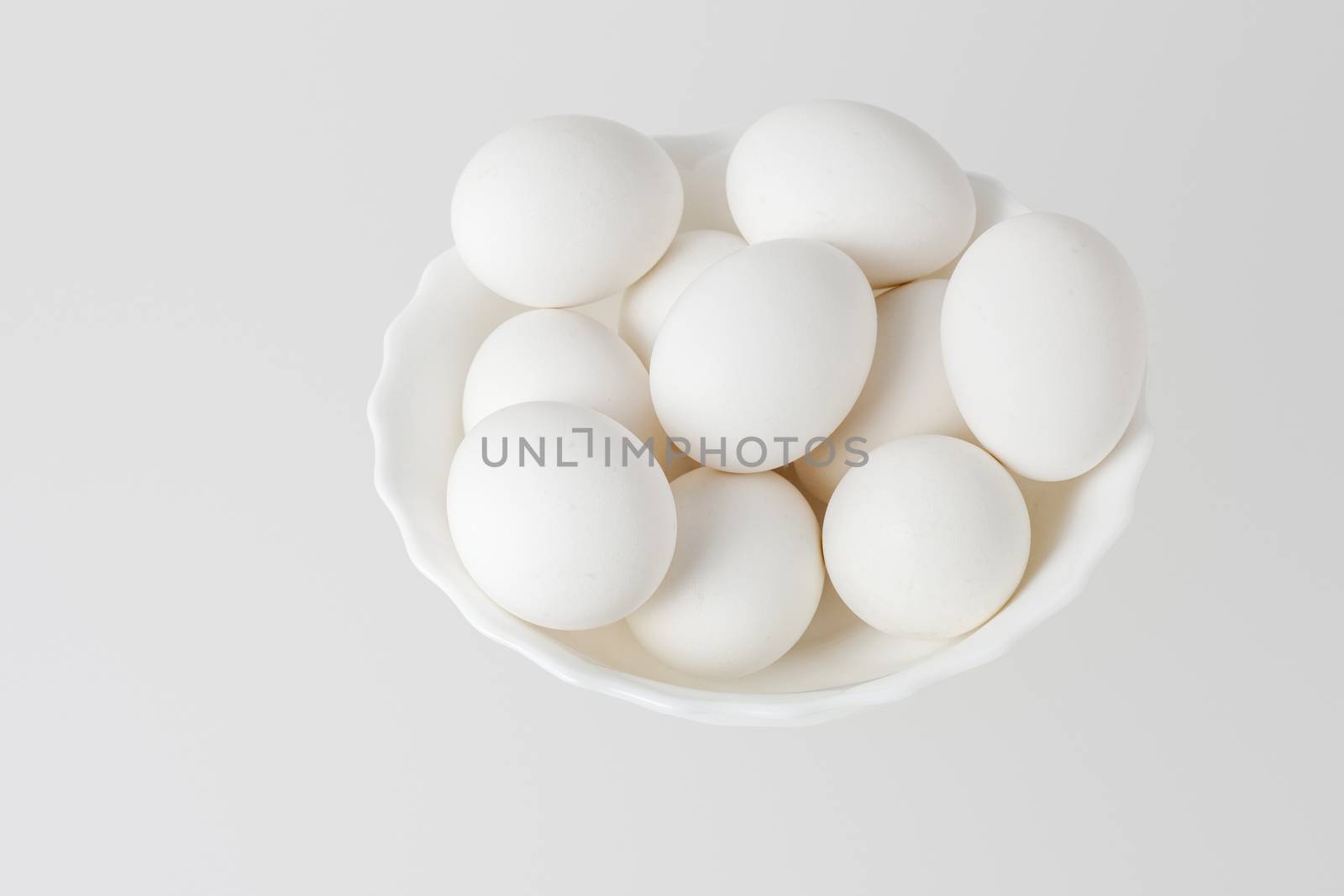 White eggs in a bowl on white background