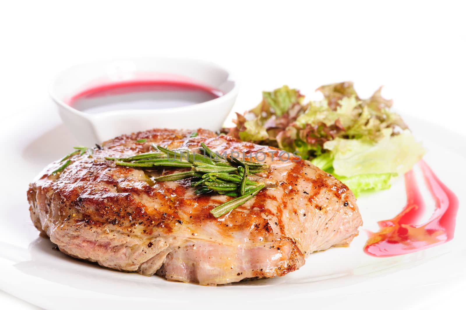 Grilled pork steaks with raspberry sauce, rosemary and leaf of lettuce