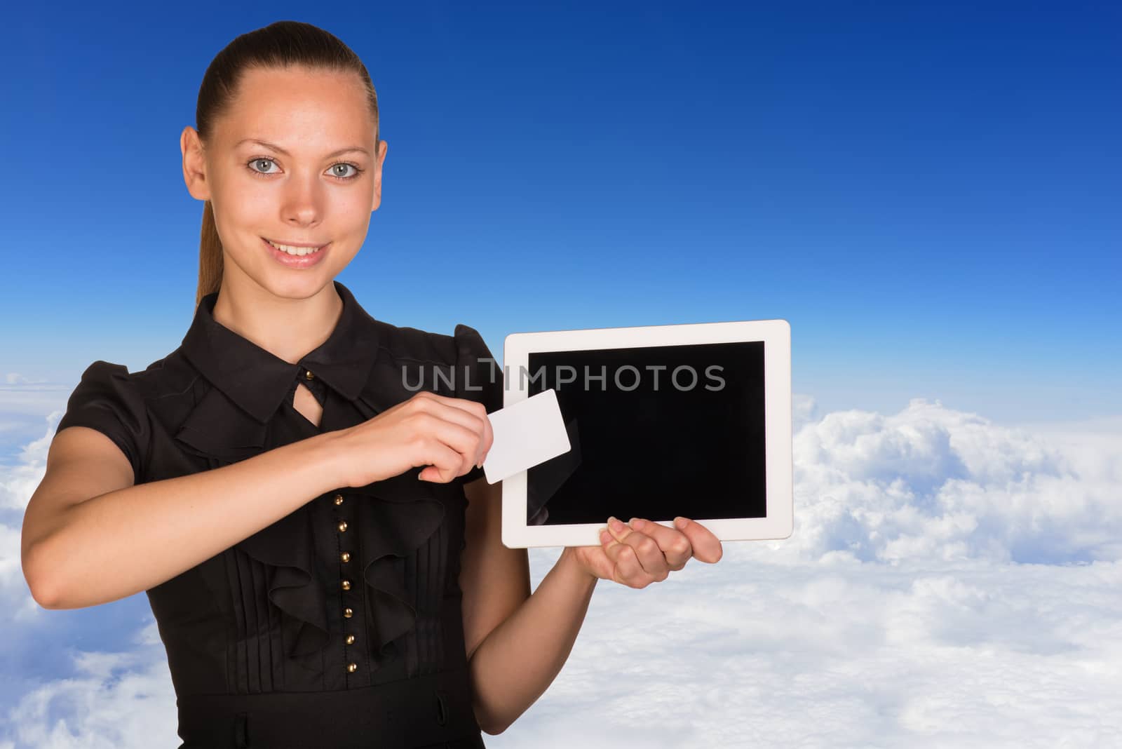 Beautiful businesswoman holding blank tablet PC and blank business card in front of PC screen. Blue sky and cloud layer as backdrop