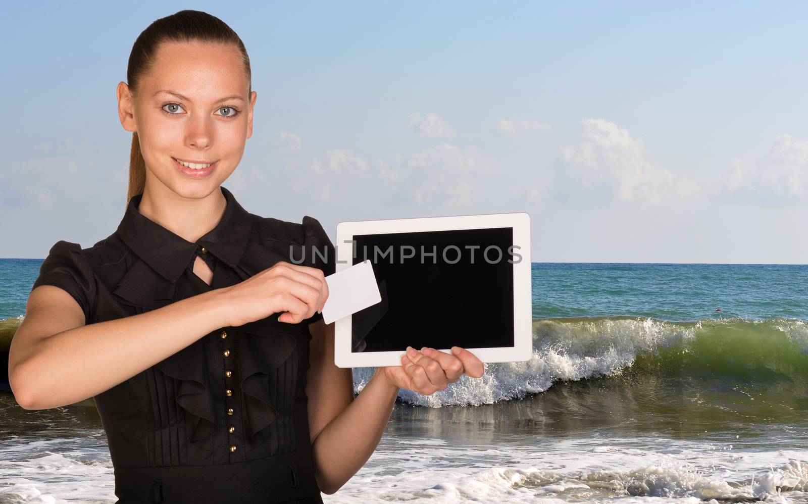 Beautiful businesswoman holding tablet PC and business card in front of screen. Seascape whith tidal waves as backdrop by cherezoff