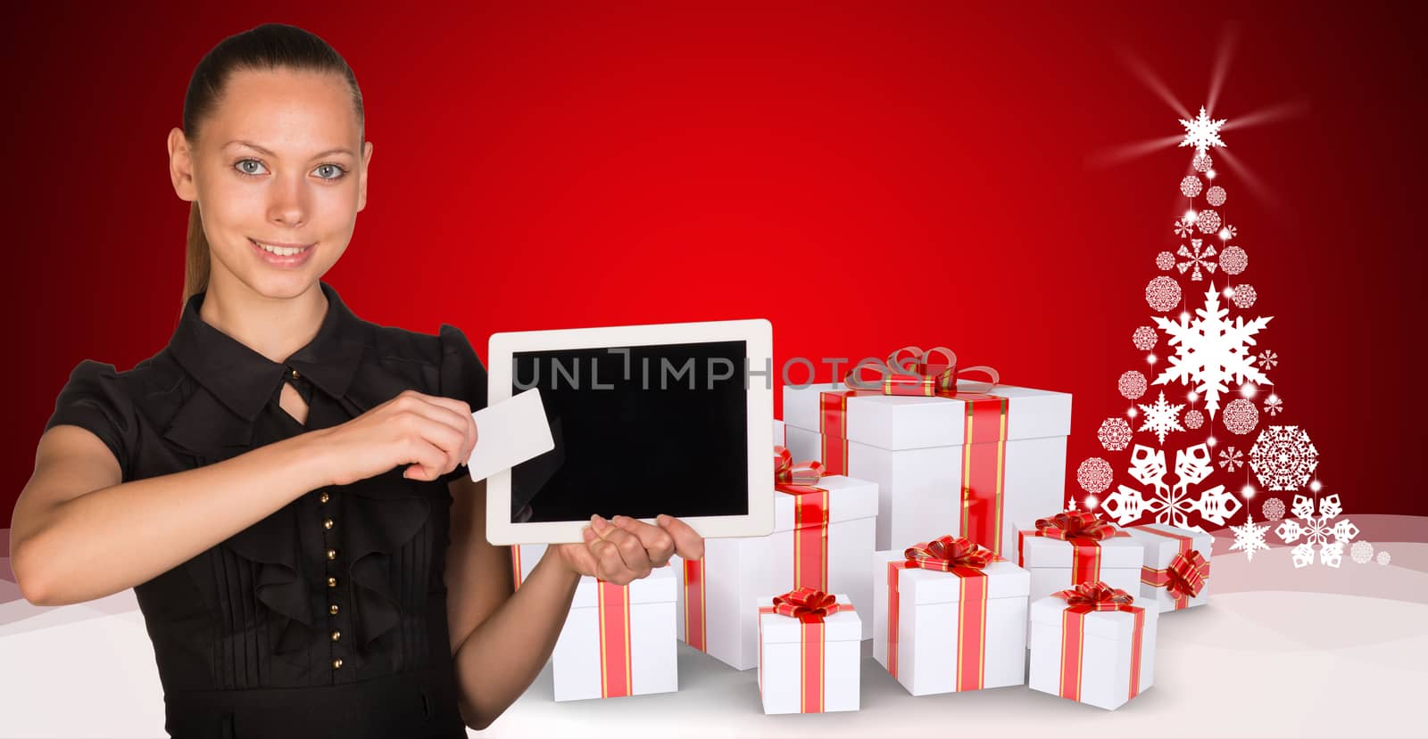 Beautiful businesswoman holding blank tablet PC and blank business card in front of PC screen. New Year tree composed of snowflakes and gifts clustered under the tree as backdrop