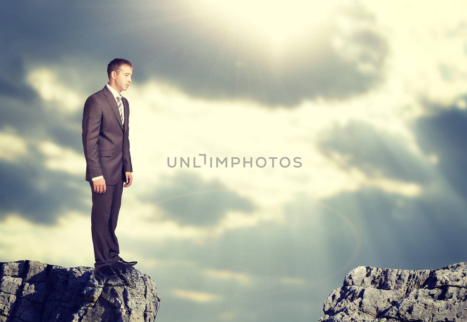 Businessman standing on the edge of rock gap by cherezoff