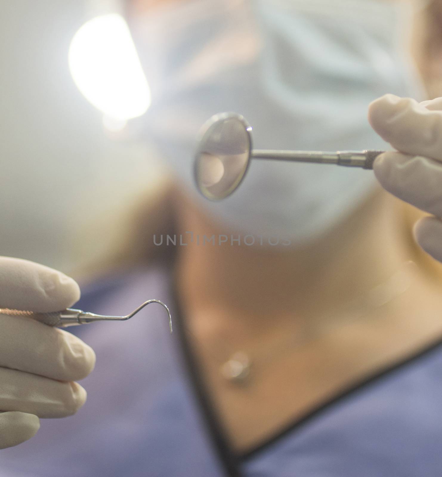 Dental instrumentation dentist pick tooth dental cleaning tool in the hand of dentist wearing face mask in dentists surgery clinic artistic color photo with shallow depth of focus.