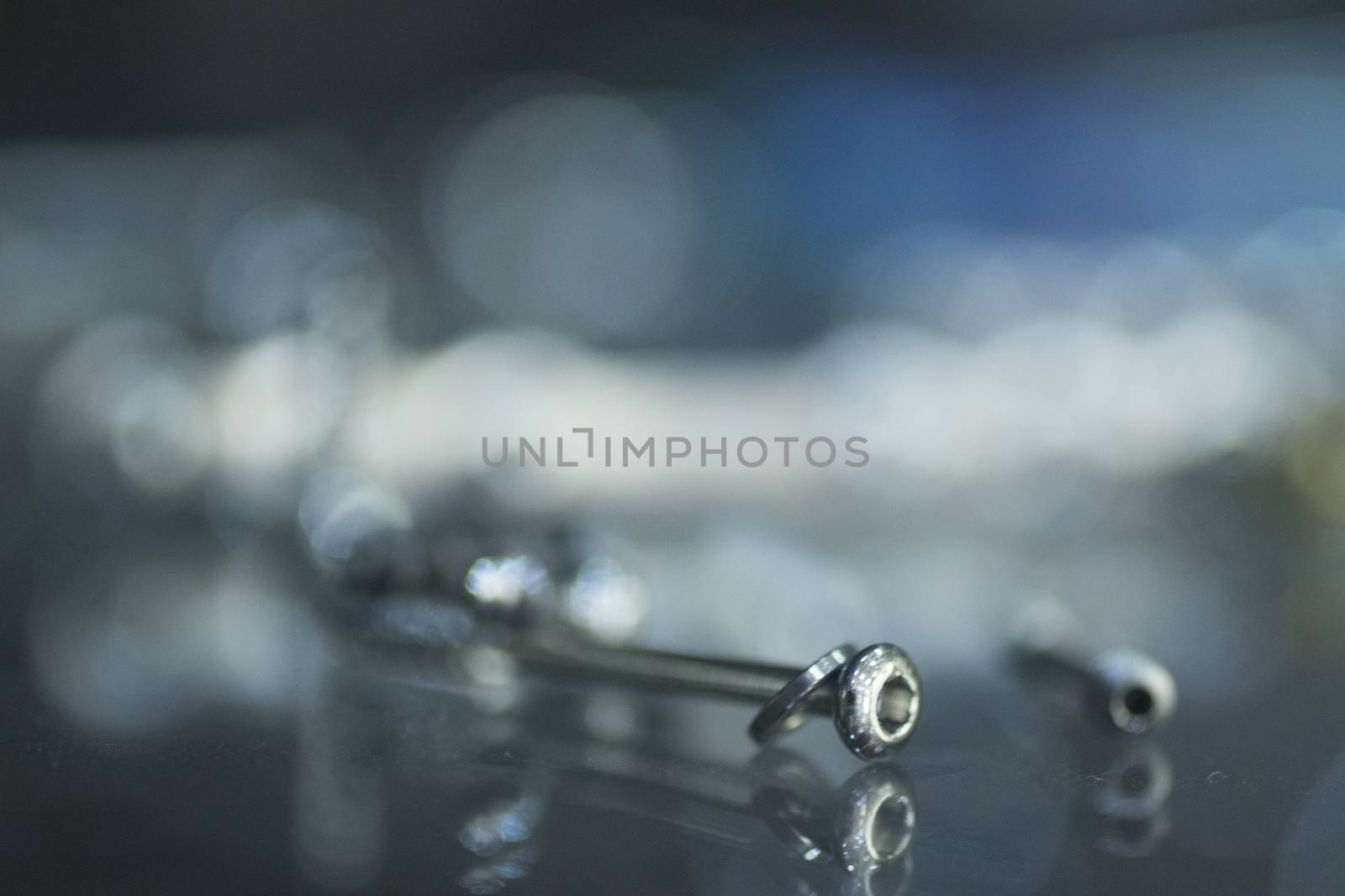Closeup macro photo of traumatology orthopedic surgery implant metal screw set against blue out of focus background. 