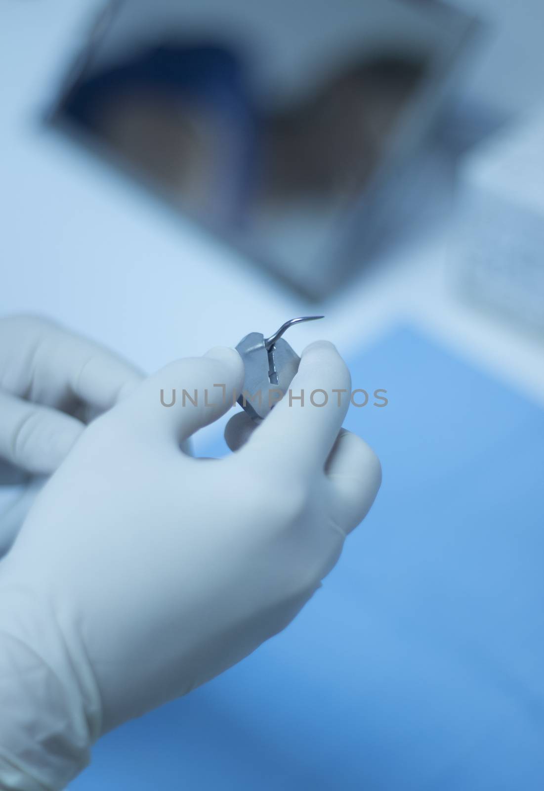 Hands of dental nurse in dental surgery clinic in white surgical sterile gloves attaching ultrasound teeth cleaning attachment prior to patient tooth clean treatment session by the dentist. 