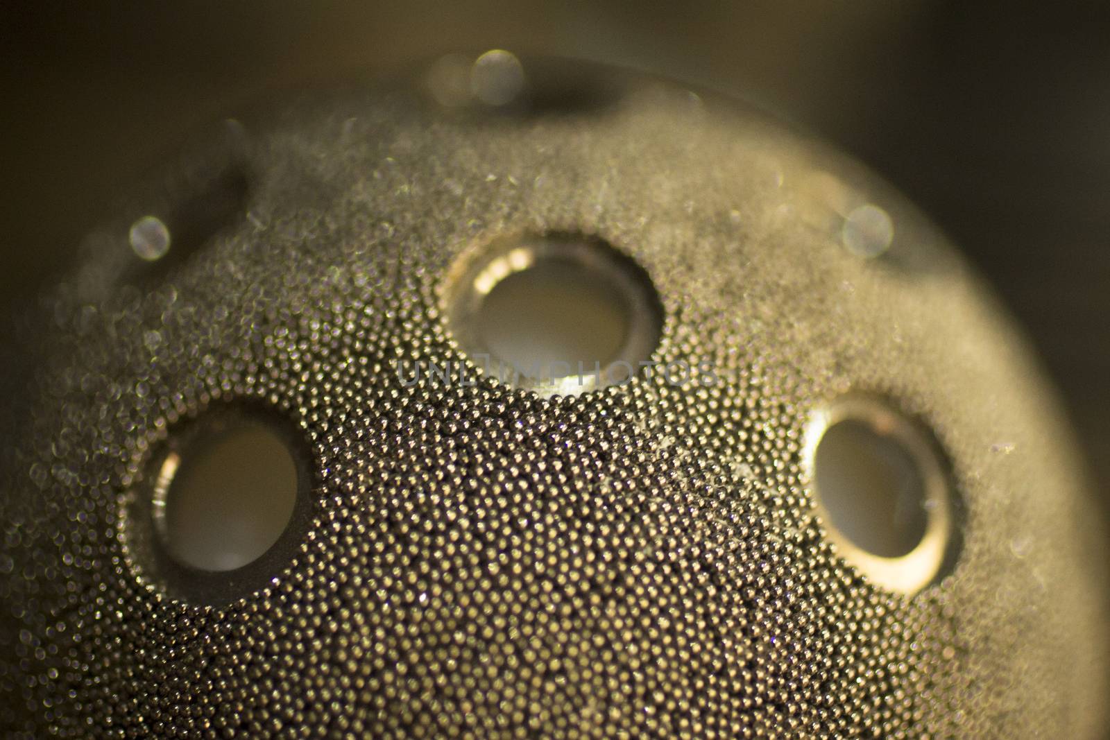 Closeup macro photograph of traumatology and orthopedic surgery metal hip ball joint implant with screw holes against plain background defocused.