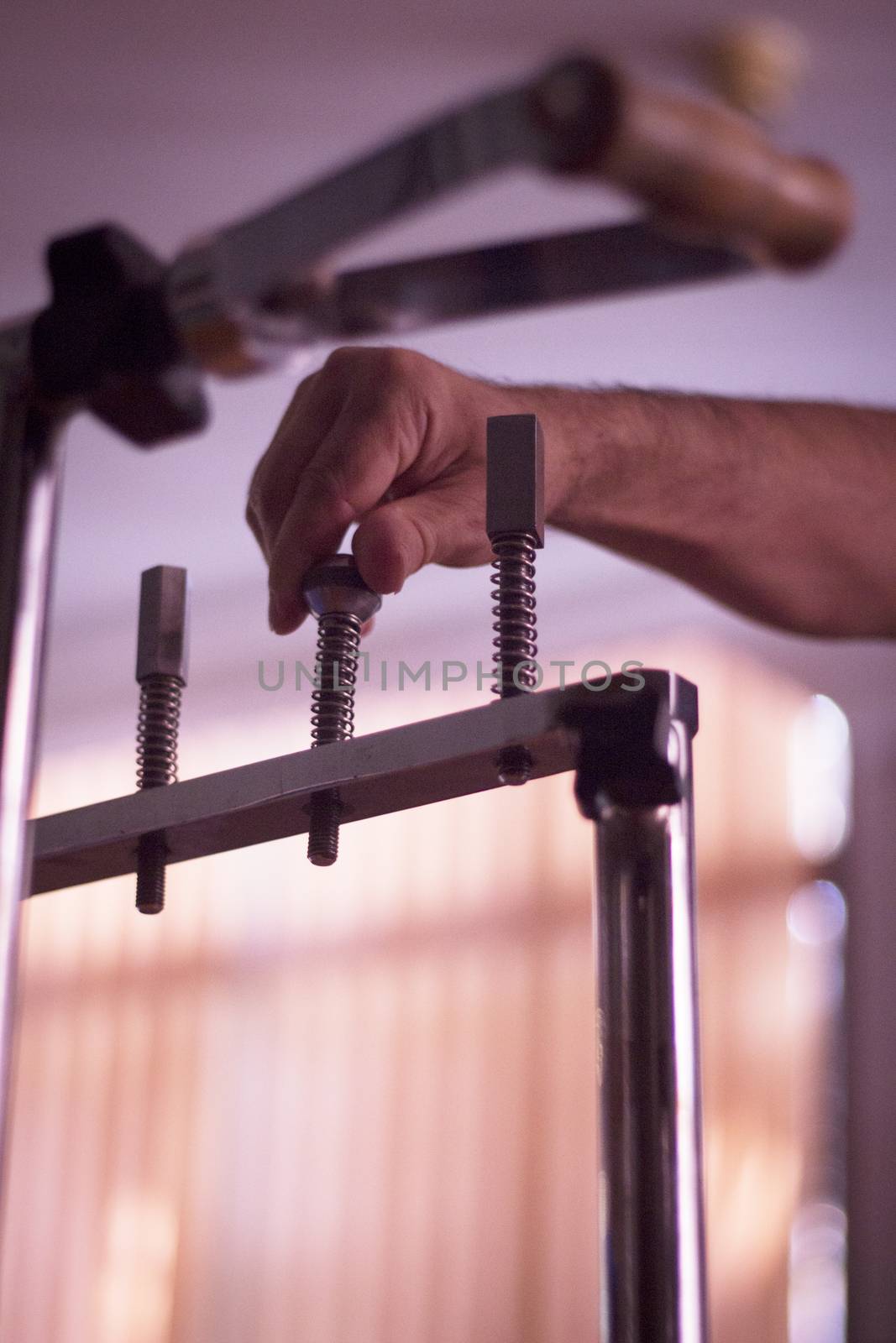 Hand of a male patient in physiotherapy rehabilitation treatment from orthopedic surgery in a hospital clinic physiotherapy room turning a screw to build strength in his fingers, hand and wrist muscles. 