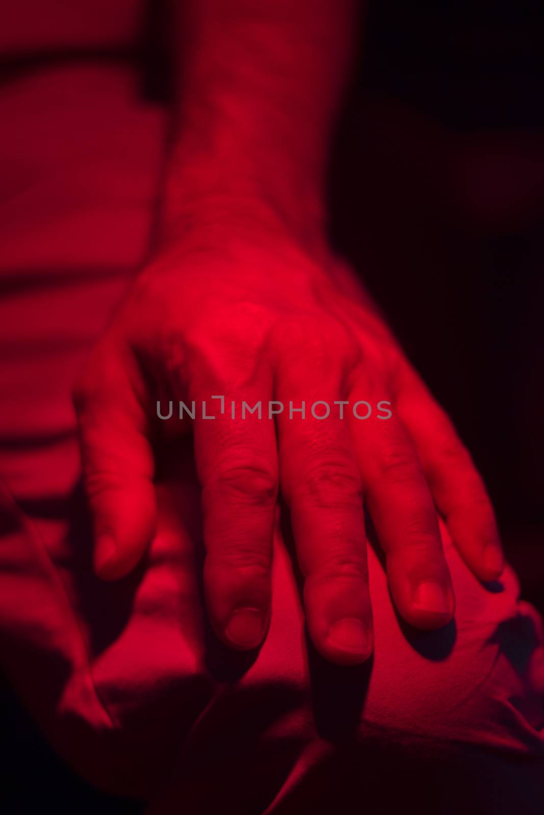 Hand of patient under red rehabilitation clinic heat lamp by edwardolive