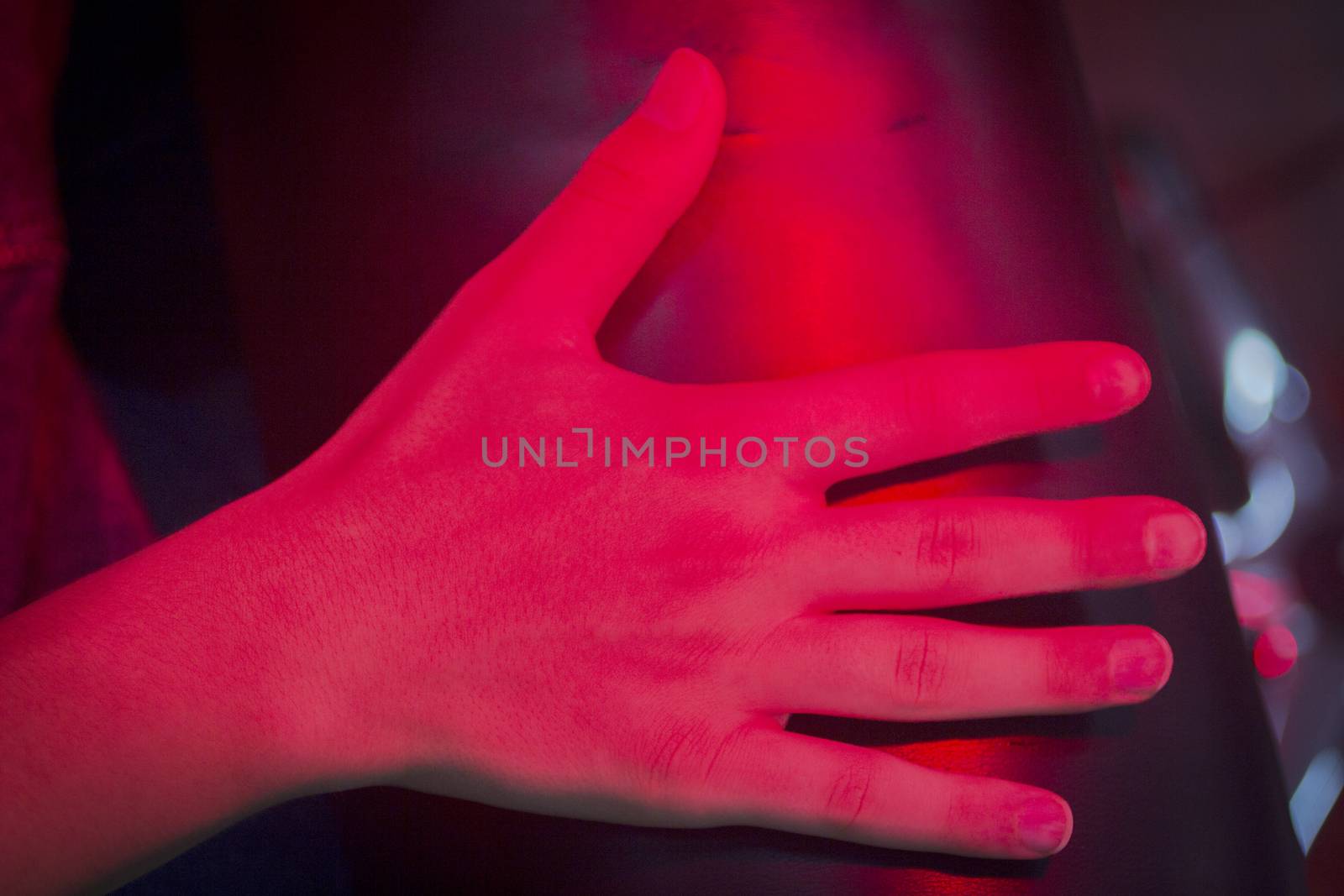 Hand of injured patient receiving treamente under red rehabilitation hospital clinic heat lamp. 