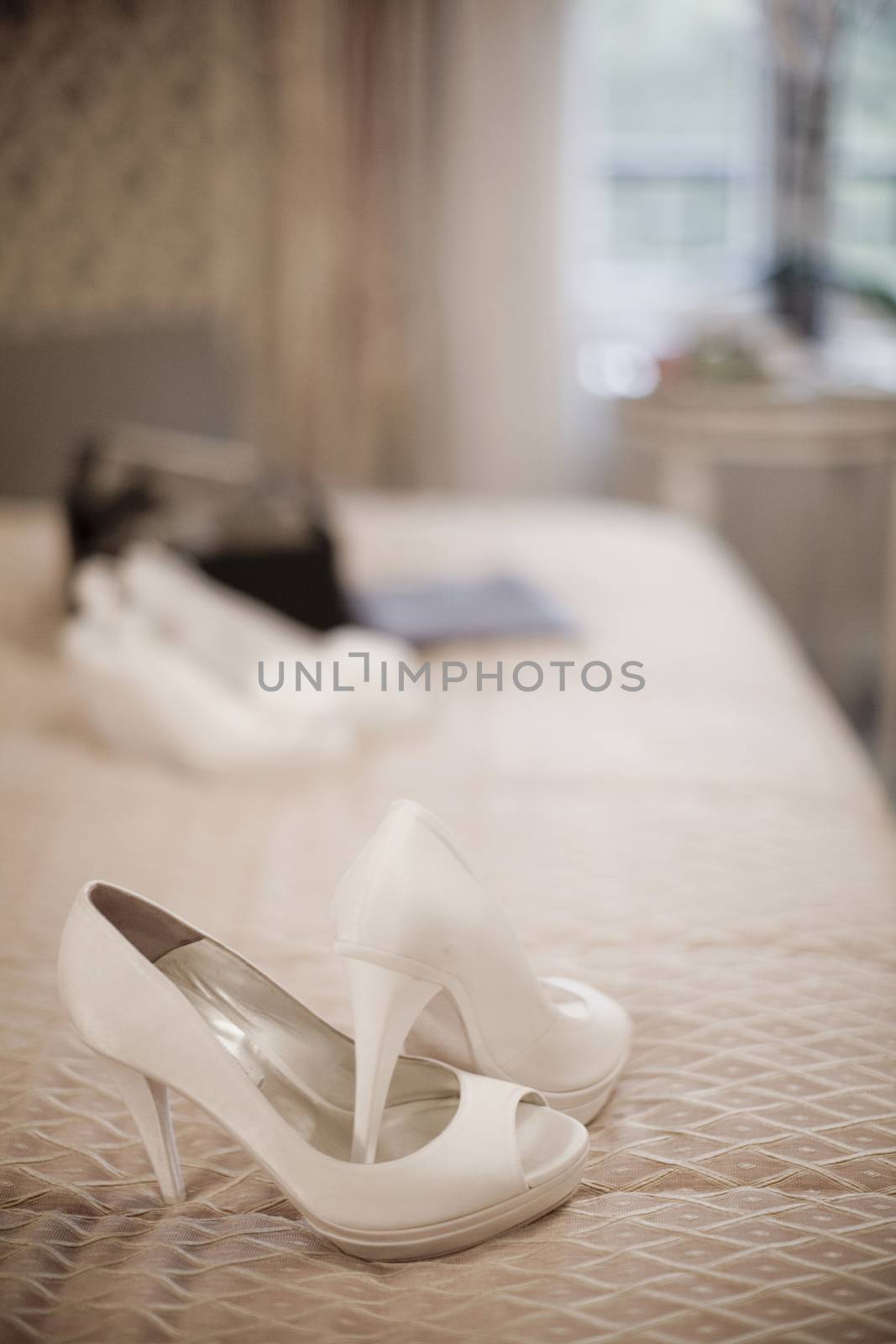 Wedding bridal white high heel shoes on bed by edwardolive