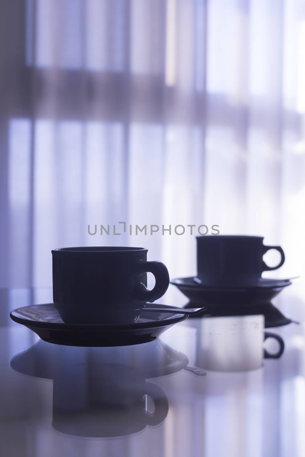 Tea or coffee cups and saucers on table silhouette by edwardolive