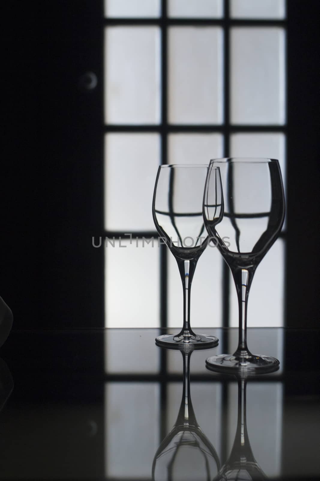 Wine glasses in dark room silhouette with door behind by edwardolive