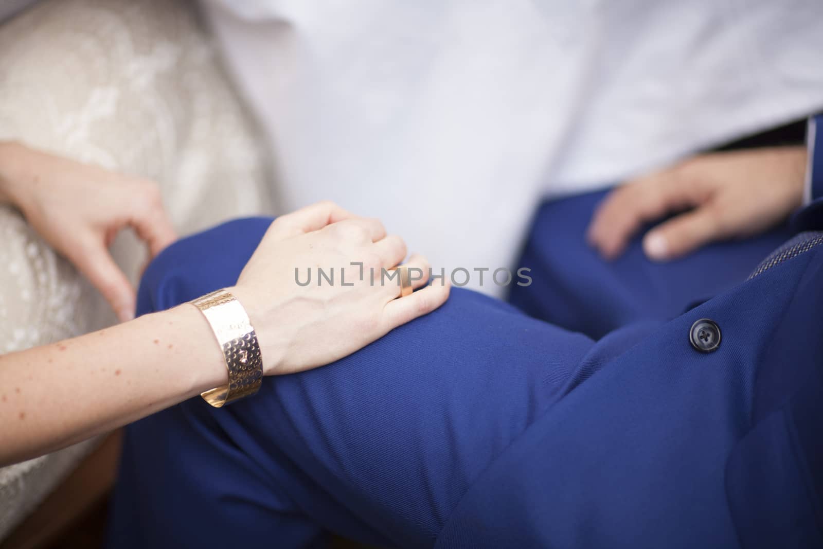 Color artistic digital photo of bridegroom in dark suit and white shirt in church religious wedding marriage ceremony holding hands with the bride in white long wedding bridal dress. Shallow depth of with background out of focus. 