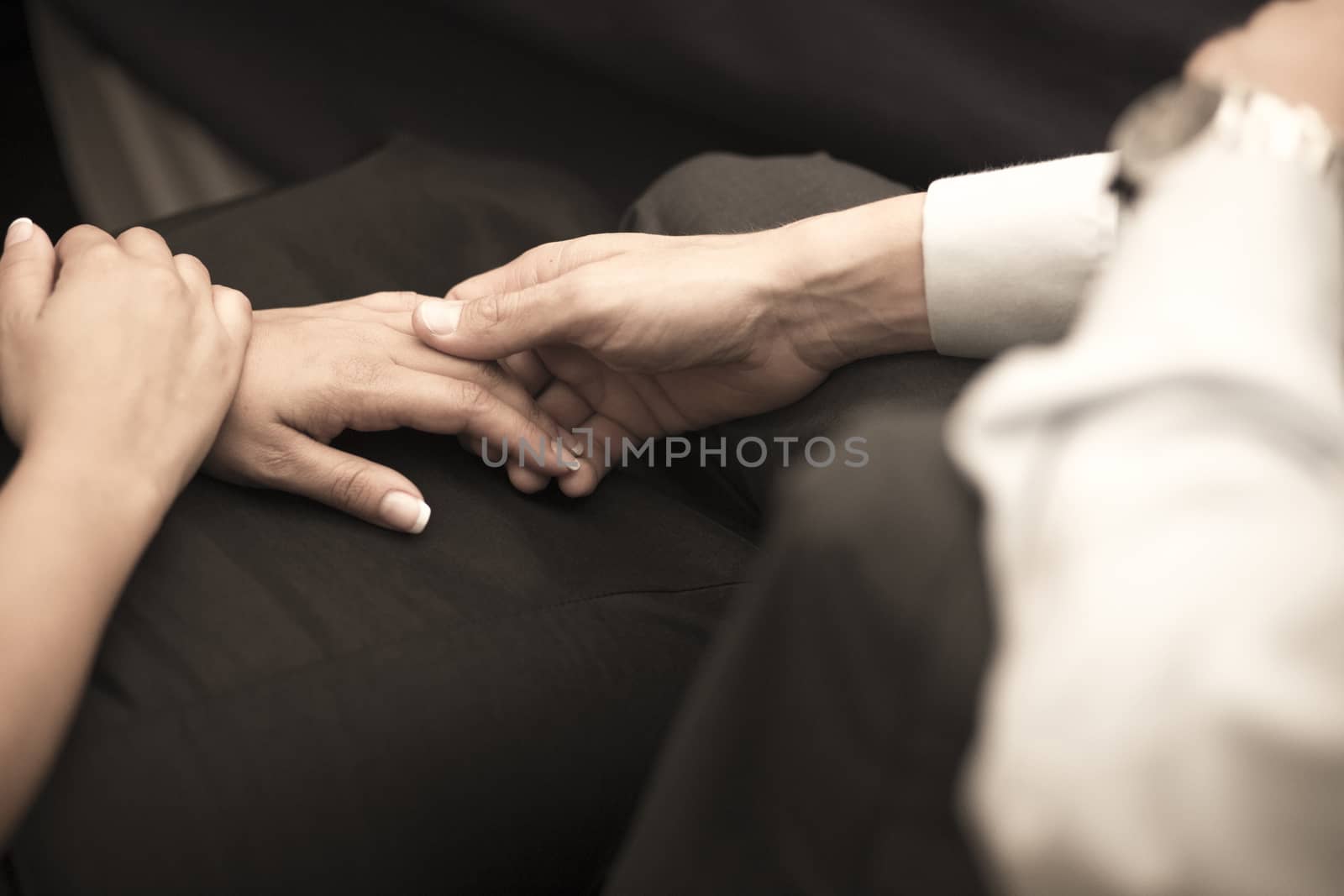 Color artistic digital rectangular horizontal photo of man wearing white suit and wrist watch and woman holding hands during wedding marriage banquet dinner in Madrid Spain. Shallow depth of on foreground with background out of focus. 