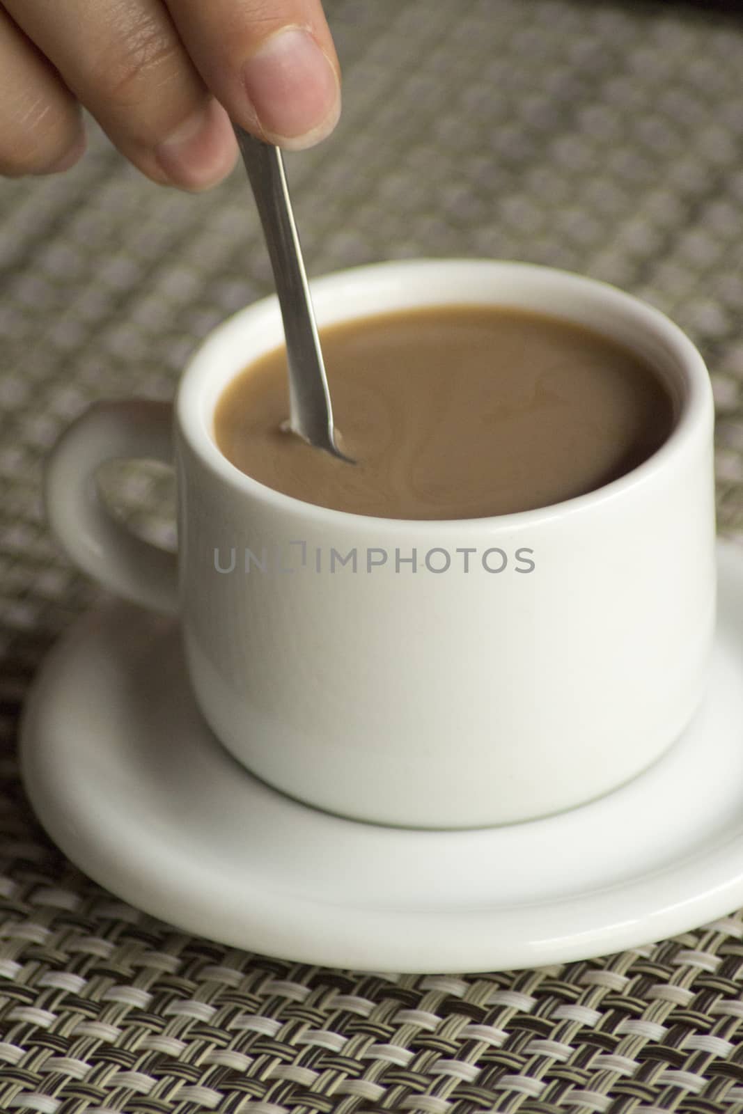 Hand stirring spoon in cup of coffee expresso by edwardolive