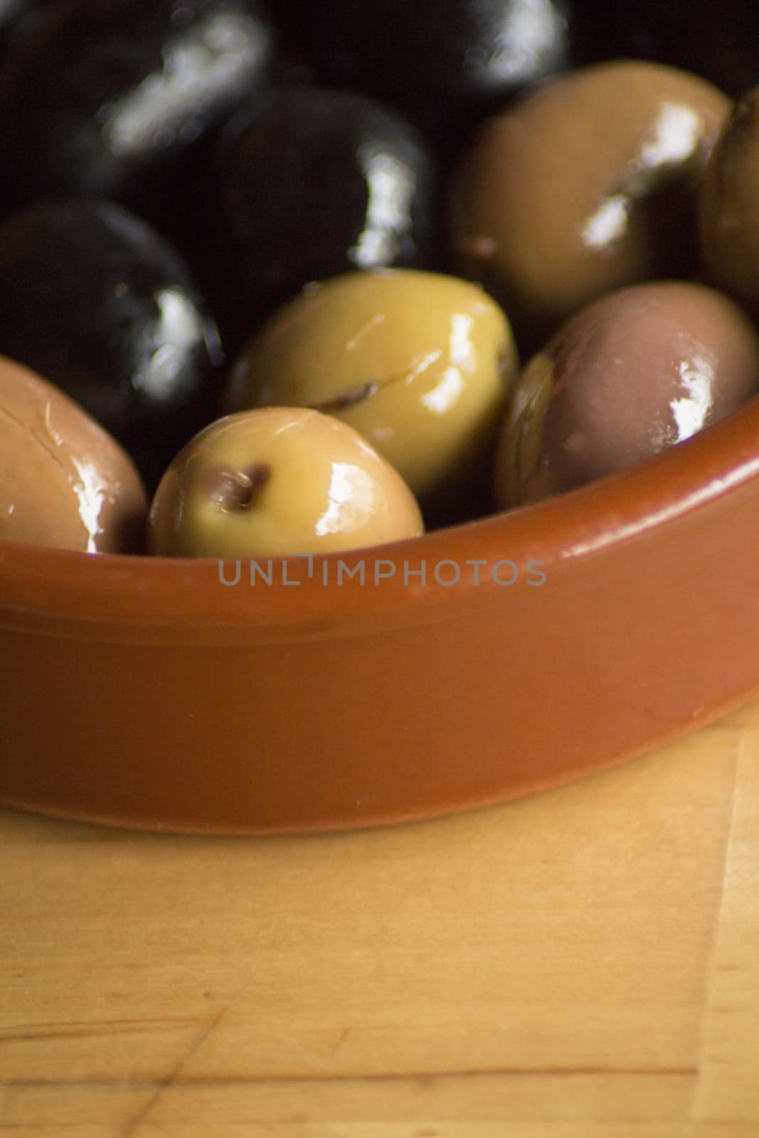 Spanish green and black olives in tapas dish on wooden table close-up macro photo in Andalusia Spain. 