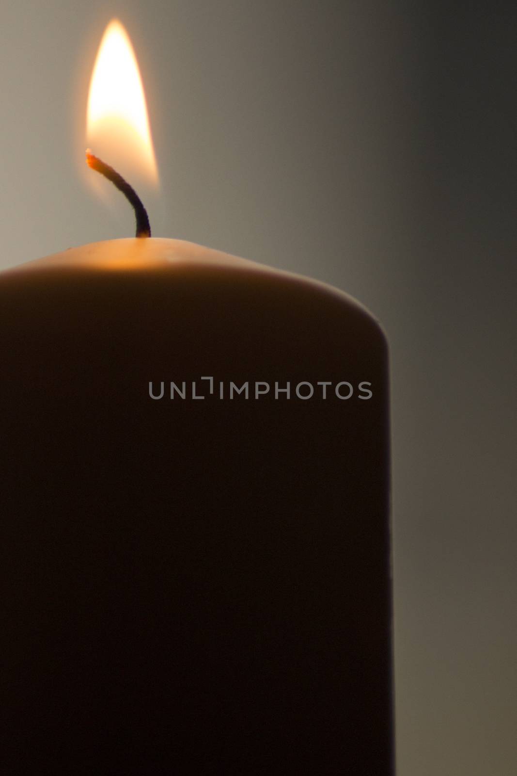 Candles burning giving off light close-up macro photo on plain background with copy space. 