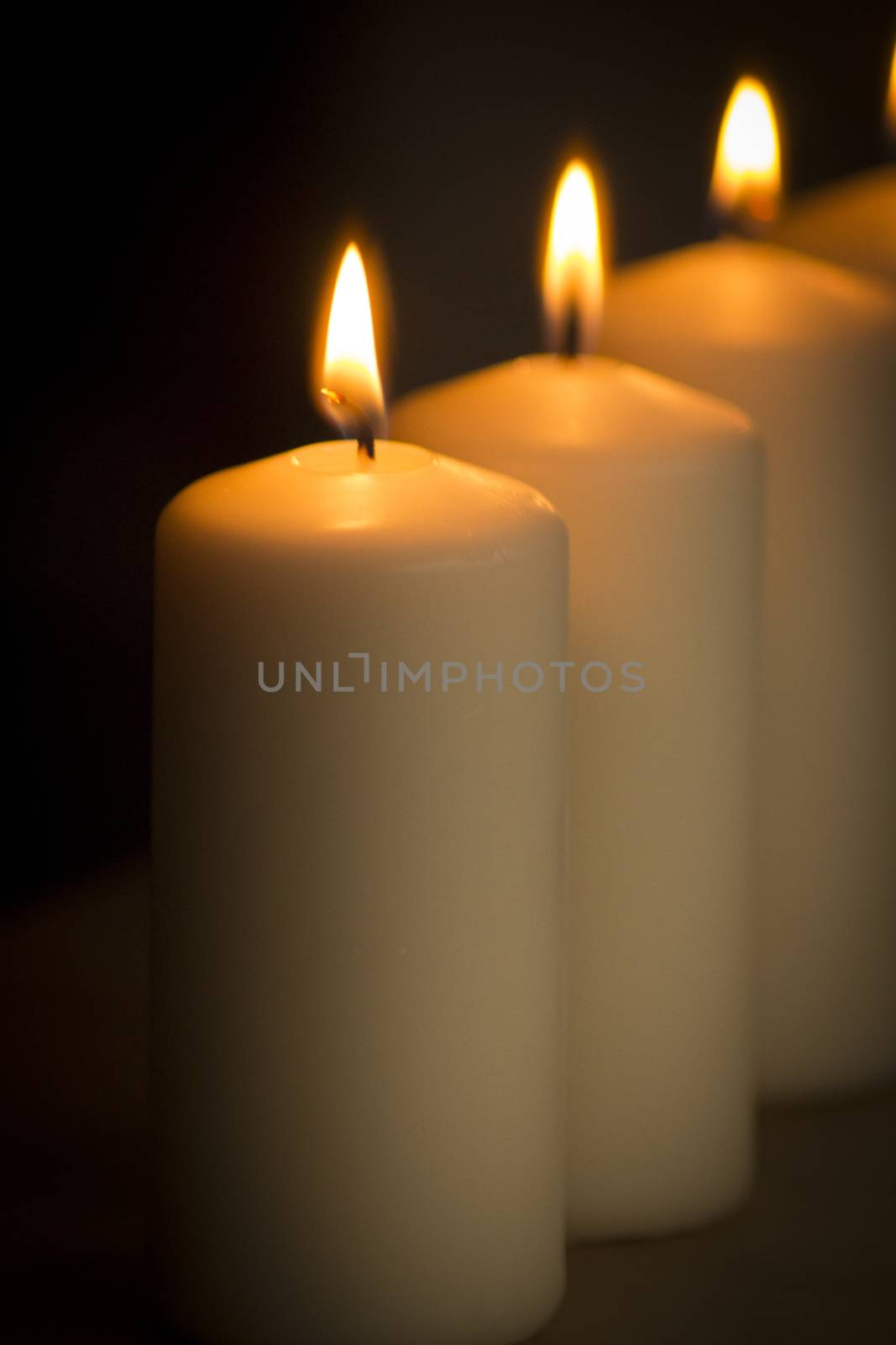 Candles lights burning close-up plain background by edwardolive