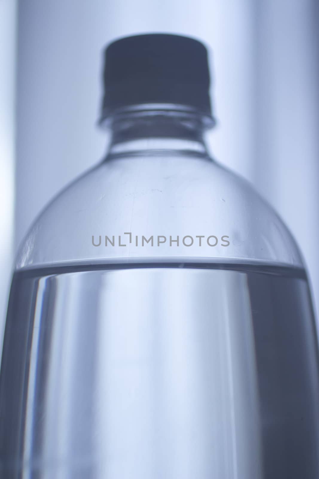 Isolated blue plastic soda lemonade soft drink bottle on a plain blue studio background close-up photo.