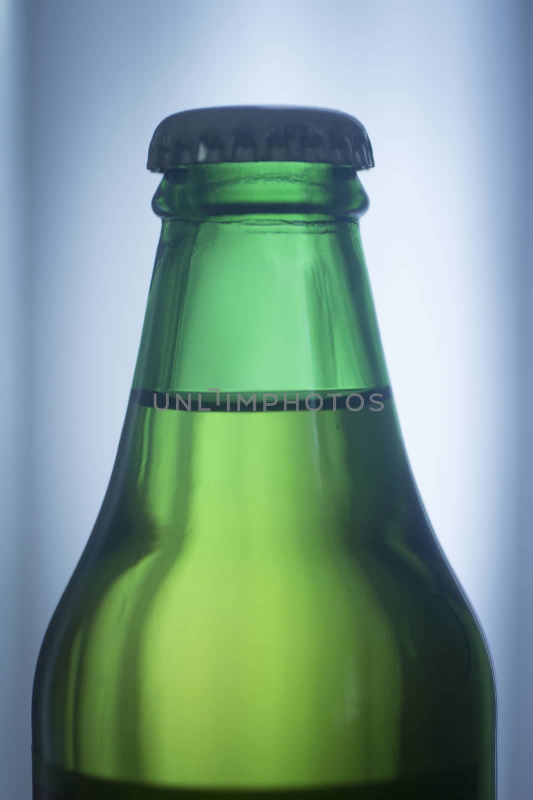 Isolated 200ml small glass Asturian Spanish apple cider bottle from Asturias Spain on a plain blue studio background close-up photo.