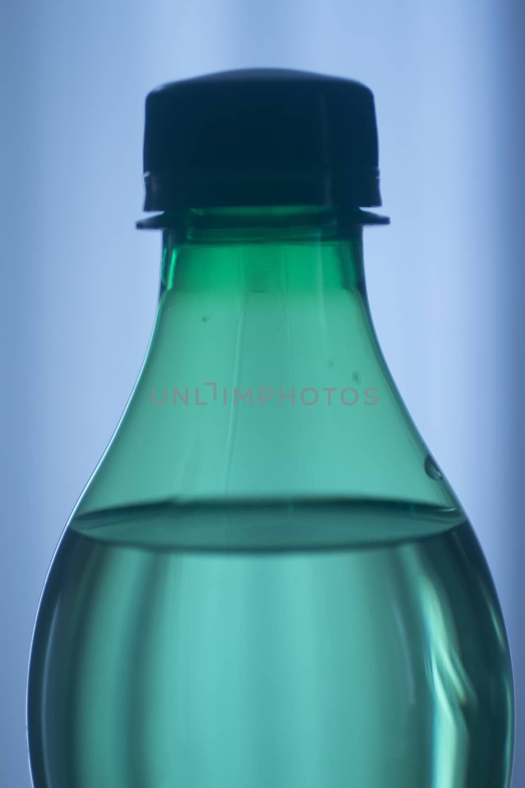 Isolated plastic water bottle on a plain blue studio background close-up photo.